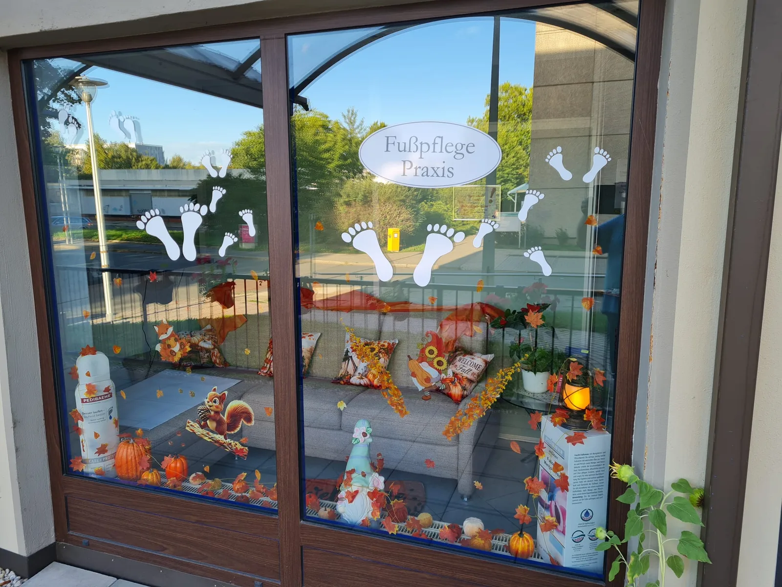 Herbstlich geschmücktes Schaufenster der Fußpflege-Praxis mit Blick auf den Wartebereich
